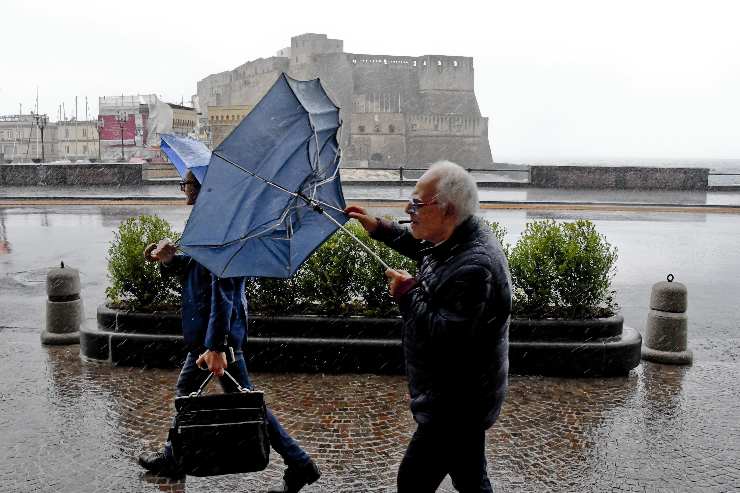 Persona cammina per Napoli con il maltempo