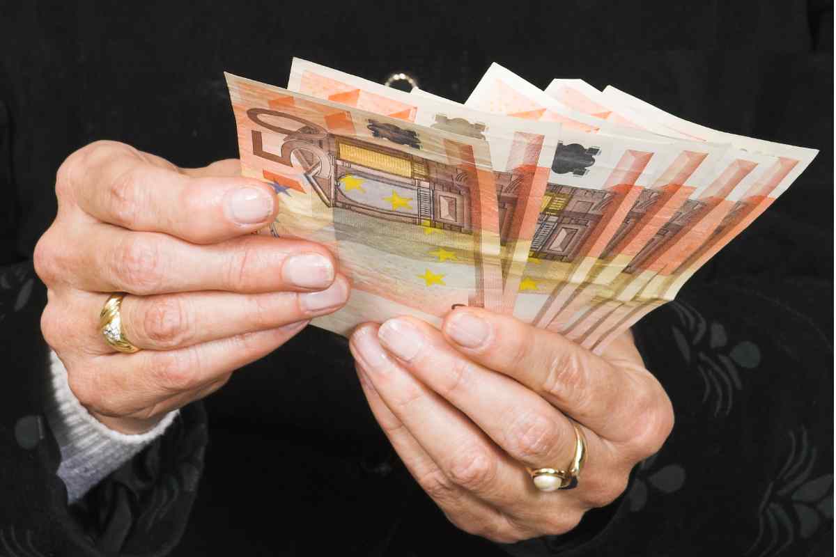Banconote da 50 euro tra due mani anziane