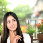 donna che pensa con balcone sotto la pioggia sullo sfondo