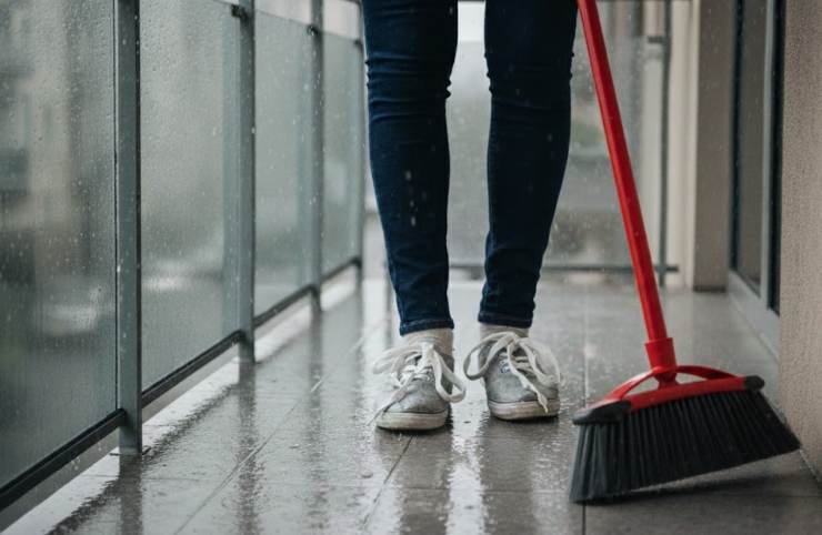donna che pulisce balcone sotto la pioggia