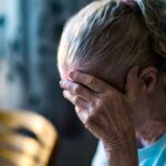 Anziana disperata con la mano sul volto