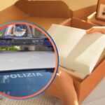 Merce da un pacco aperto ed auto della polizia in piccolo