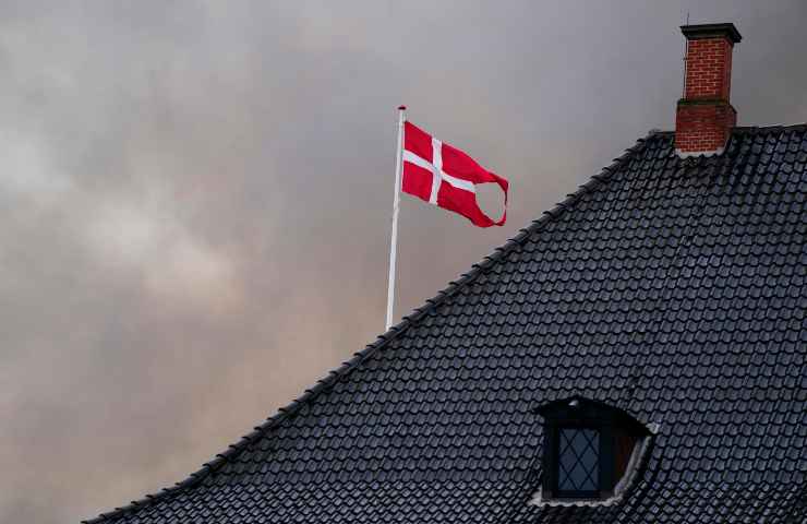 Bandiera della Danimarca su un tetto con cielo nuvoloso come sfondo