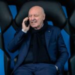 Beppe Marotta seduto al telefono con una mano in tasca