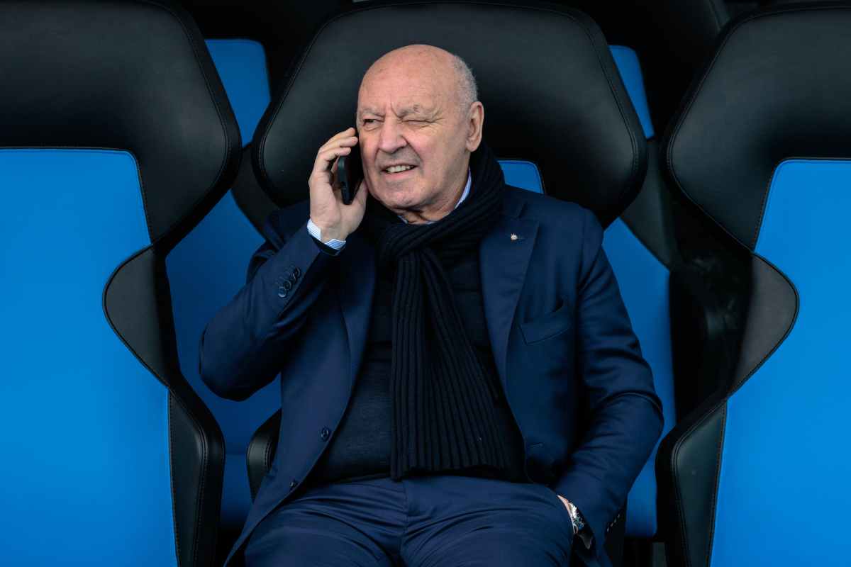 Beppe Marotta seduto al telefono con una mano in tasca