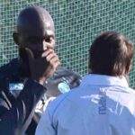 Romelu Lukaku si copre la bocca mentre parla ad Antonio Conte di fronte a lui e ritratto di spalle.