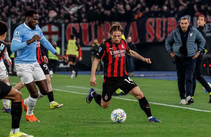 Luka Modric gestisce il pallone in favore del Milan contrastato da un calciatore della Lazio con l'allenatore dei romani Maurizio Sarri sullo sfondo.