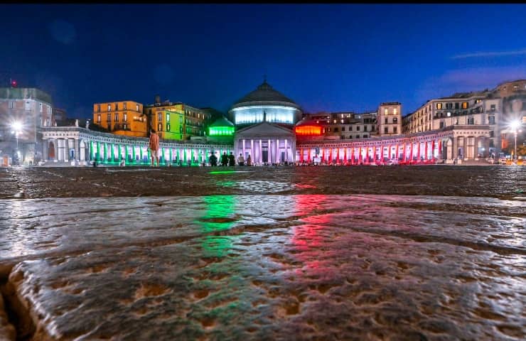 Piazza del Plebiscito a Napoli di notte mentre è illuminata con i colori della bandiera italiana.
