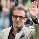 Alessandro Del Piero con occhiali fumè e giacca bianca saluta.