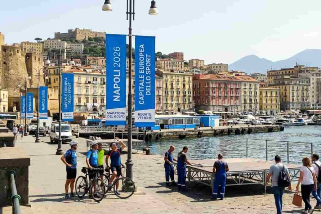 Allestimenti per Napoli Capitale dello Sport 2026 sul lungomare con vista su Castel dell'Ovo e il Vesuvio.