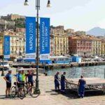 Allestimenti per Napoli Capitale dello Sport 2026 sul lungomare con vista su Castel dell'Ovo e il Vesuvio.