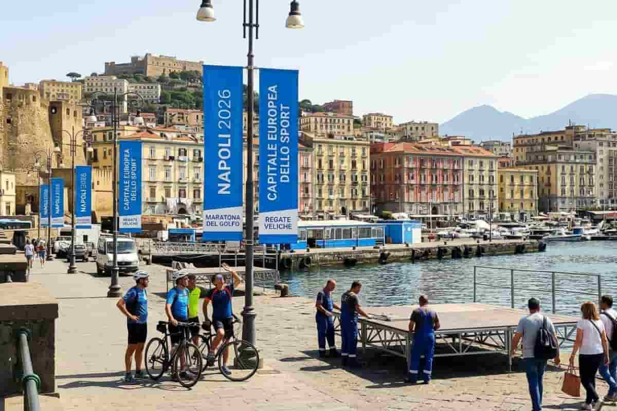 Allestimenti per Napoli Capitale dello Sport 2026 sul lungomare con vista su Castel dell'Ovo e il Vesuvio.