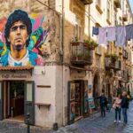 Street art Napoli Quartieri Spagnoli murales Maradona. Vicolo con panni stesi, turisti e vista sul Golfo.