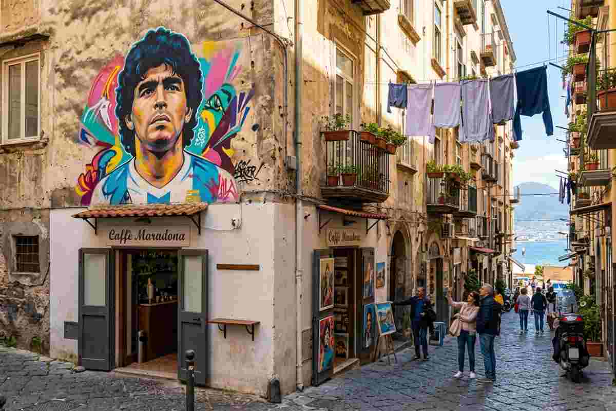 Street art Napoli Quartieri Spagnoli murales Maradona. Vicolo con panni stesi, turisti e vista sul Golfo.