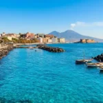 Lungomare Caracciolo Napoli con Castel dell'Ovo, Vesuvio e mare azzurro limpido.