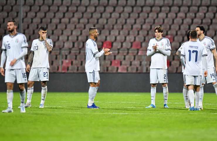 Calciatori dell'Italia in tenuta di gioco bianca da trasferta delusi in campo.